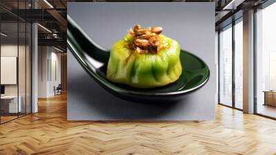 A green squash and pork dumpling with roasted garlic, served in a spoon and isolated on a grey background, representing a popular dish from Hong Kong. Wall mural