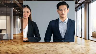 A studio portrait features a youthful, attractive male executive alongside an experienced Asian female professional set against a neutral backdrop. Wall mural