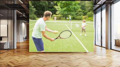 Family playing tennis on grass court Wall mural