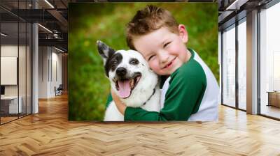 Child lovingly embraces his pet dog, a blue heeler Wall mural