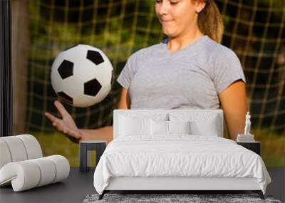 Teen girl juggling soccer ball with her knees Wall mural