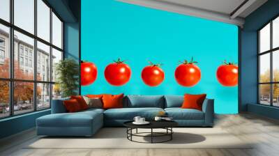 Symmetrical line of five ripe red tomatoes on blue Wall mural