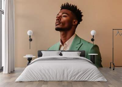 Confident young African American man in a stylish green suit gazing upward against a neutral background Wall mural