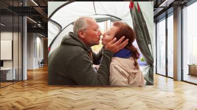 Elderly couple kissing on mouth sitting in tent Wall mural