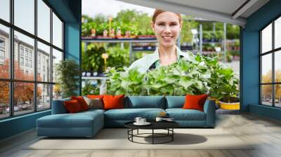 Horticultural trainee carries plants in the garden center Wall mural