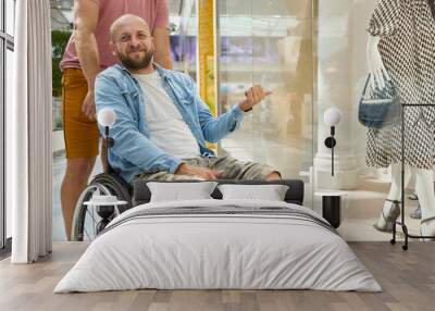 Man using a wheelchair in a shopping mall interacting with a fashion store display Wall mural