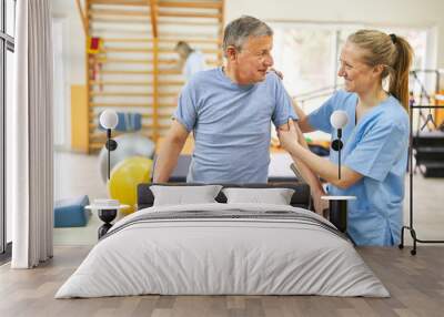 Physiotherapist assisting senior man in movement therapy Wall mural