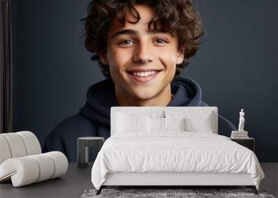 Smiling teenage boy with curly hair on a solid background Wall mural