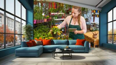 Young florist in flower shop doing quality control Wall mural