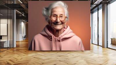 Conceptual portrait photography of a grinning woman in her 70s wearing a stylish hoodie against a pastel or soft colors background. Generative AI Wall mural