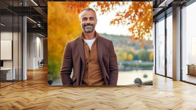 Handsome mature man in a brown jacket on a background of autumn park Wall mural