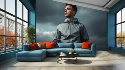 Handsome young man in sportswear on cloudy sky background Wall mural