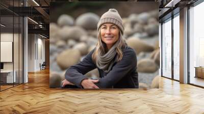 Portrait of a smiling mature woman sitting on pebble beach Wall mural