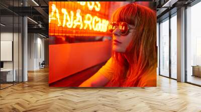 Portrait of ginger woman with sunglasses and yellow t shirt on red neon lights Wall mural