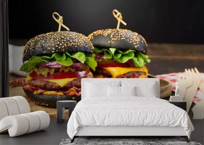 Two huge black hamburgers on dark wooden background Wall mural