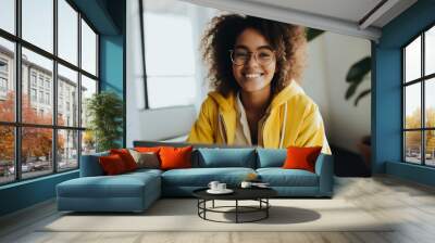 an African girl with a lush hairstyle in a yellow jacket is sitting at a notebook. remote work generative ai. Wall mural