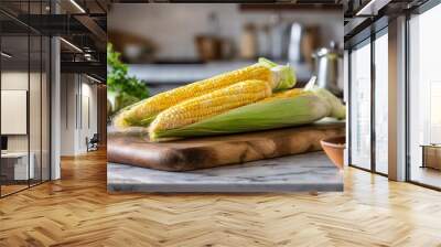 A selection of fresh vegetable: sweet corn, sitting on a chopping board against blurred kitchen background; copy space Wall mural