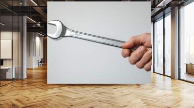 Hand Holding Metal Wrench Tool Against White Background
 Wall mural