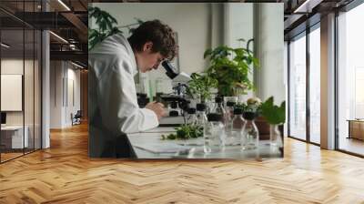 Scientist in lab coat meticulously examining potato plant under microscope, surrounded by various potato samples and research tools on a clean white table. Focus on agricultural research and plant sci Wall mural