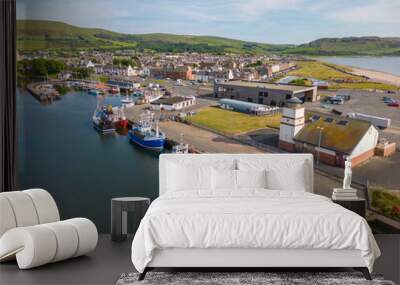 This aerial drone photo shows the harbour of Girvan at the Irish Sea in Scotland. There are many fisher boats docked in this port. Girvan is a small town and it is sunny summer weather.  Wall mural