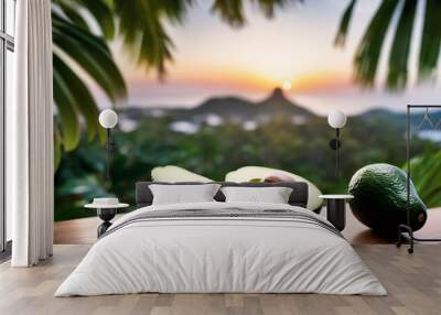 Avocado fruit on wooden table with tropical island in background Wall mural