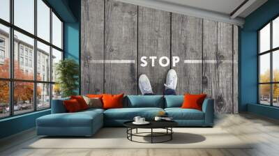 Man standing on the wooden boards with stop message on the floor, point of view perspective used. Wall mural