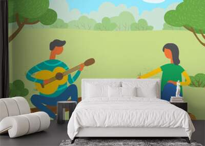 Man and woman friends camping. They are sitting around camp fire and playing guitar, toast marshmallows. Tourist group on a forest walk or holiday camp play music, cook food at the stake on a weekend Wall mural