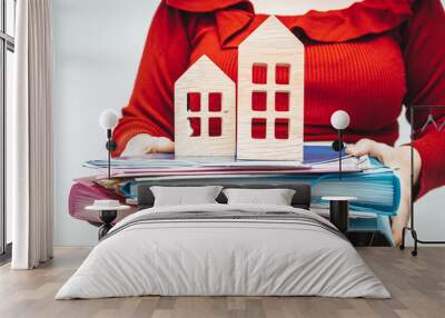 A pile of documents needed when buying a house, Credit formalities, Dealing with housing matters in offices, A woman holds a pile of documents and wooden houses Wall mural