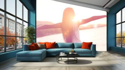 Beautiful girl walking on the beach at sunset, freedom concept Wall mural