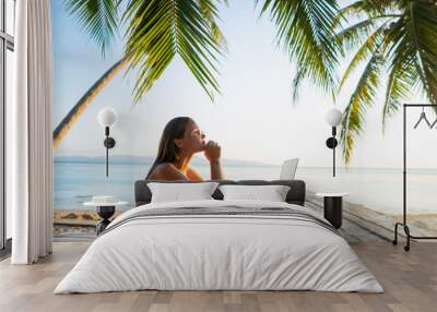 freelancer girl with a computer among tropical palm trees work on the island in sunset Wall mural