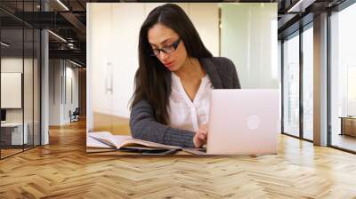 A college student does her homework on her laptop in the library. A girl reads and works using her pc at the library Wall mural