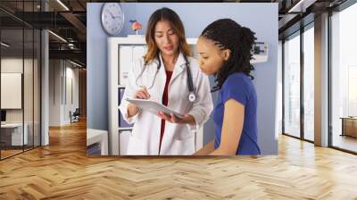 African American patient explaining issues to Asian doctor using tablet Wall mural