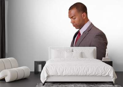 An African American businessman crosses his arms and then looks at his smart phone on white background. A black executive uses his mobile phone for work on a blank backdrop Wall mural