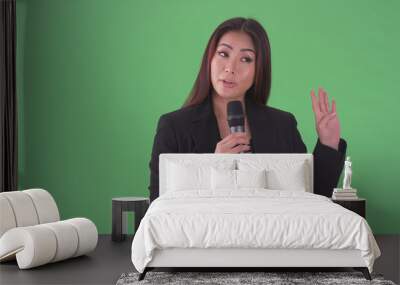 Asian millennial businesswoman speaking through microphone on green screen Wall mural