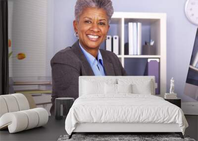 Black businesswoman sitting at desk smiling Wall mural