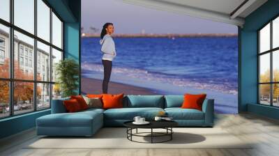 Black woman enjoying the ocean view until waves come Wall mural