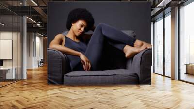 Black woman sitting in chair thinking Wall mural