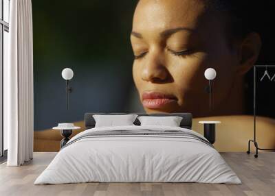 black woman sitting with eyes closed outdoors Wall mural