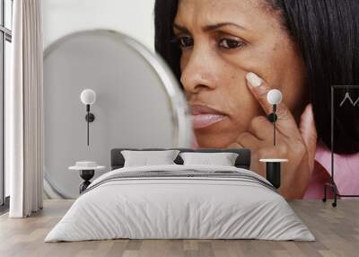 Closeup of black middle aged woman looking into mirror Wall mural