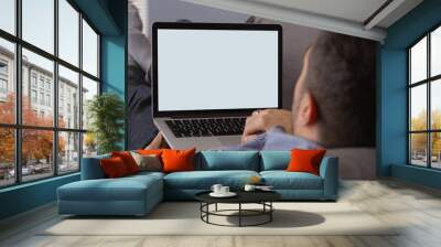 Hispanic man using laptop on couch Wall mural