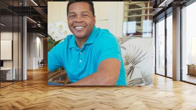 Portrait of attractive Black man smiling and sitting on porch looking at camera Wall mural