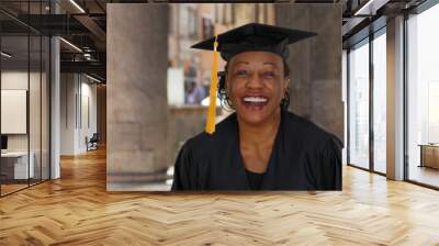 Portrait of senior black woman in graduation gown smiling and cheering Wall mural