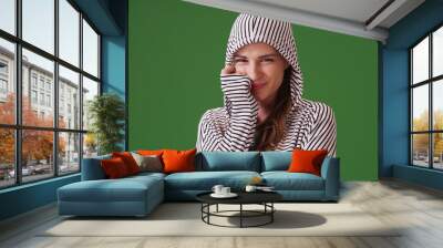 Portrait of woman wearing hoodie smiling at camera on green screen Wall mural