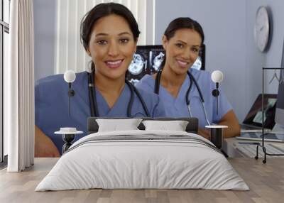 smiling hispanic and african american nurses sitting at computer station Wall mural