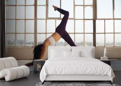 Young active woman practicing yoga by large open window in urban space Wall mural