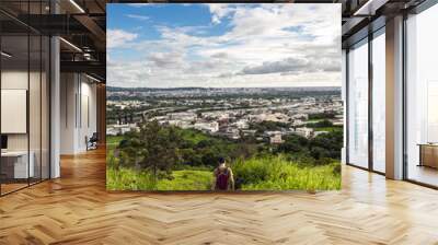 hiker and view of city from the beautiful mountain. Blue sky and green meadow. Wall mural