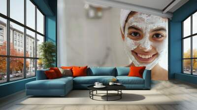 Smiling teen girl with a facial mask in a bathroom, wearing a towel Wall mural