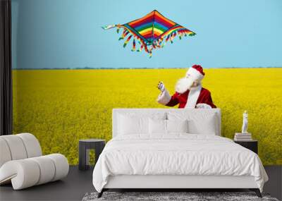 Christmas Santa Claus fling a kite in blooming yellow field. Spring vacation concept. Wall mural