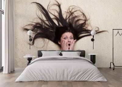 Portrait of a shocked girl with long hair lying on the floor Wall mural