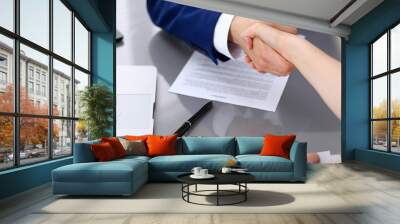 Businessman and business woman shaking hands to each other above signed contract Wall mural